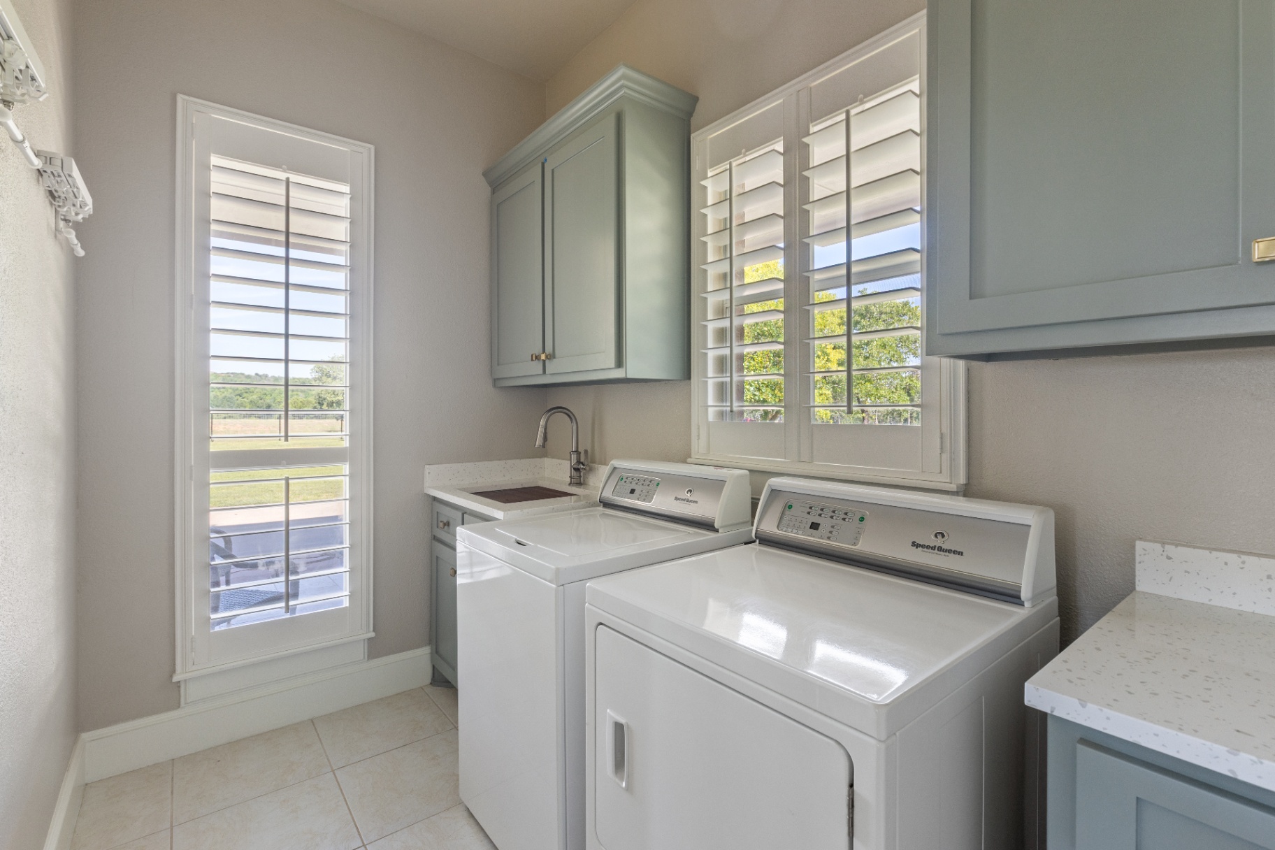 Laundry with sage cabinetry and Speed Queen