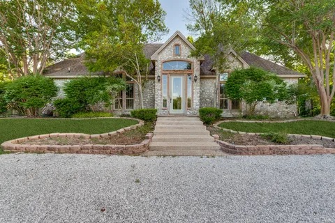 Stone-and-brick front exterior with arched entry and manicured landscaping